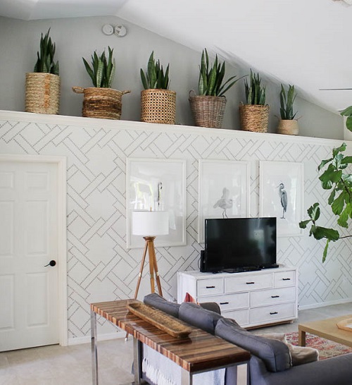 A comfortable living room with a couch, table, and a snake plant adorning the wal